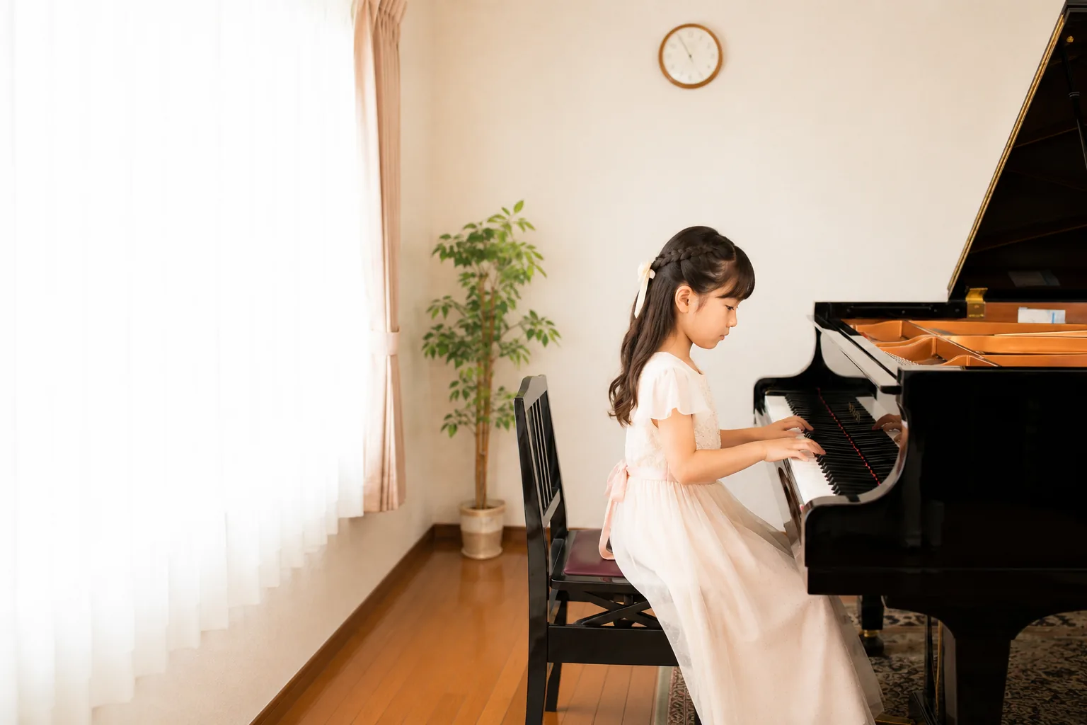 ドレスを着た女の子がグランドピアノを弾いている様子